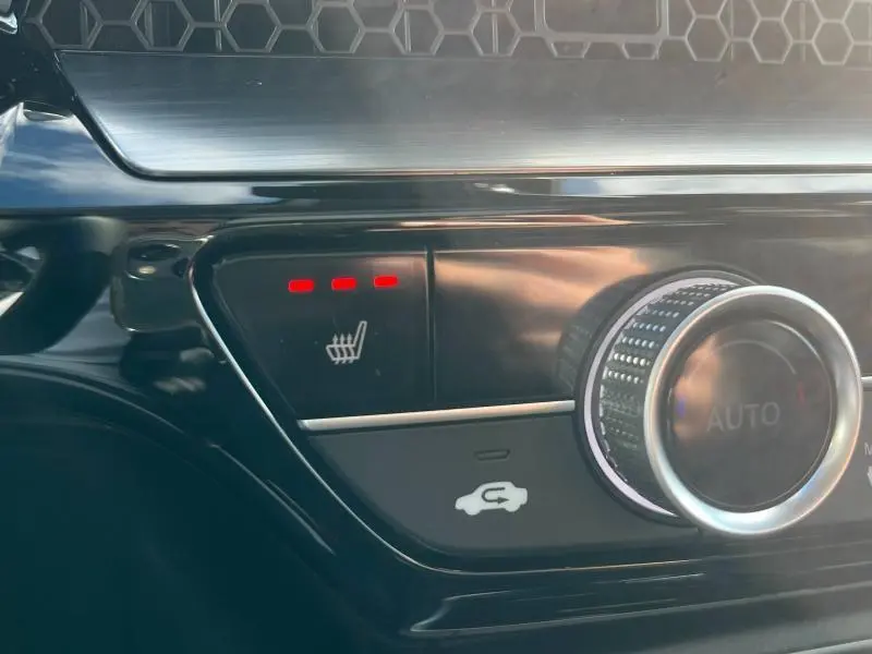 Gros plan sur le bouton de siège chauffant activé avec trois voyants rouges sur la console intérieure noire du Honda CR-V 2024.
