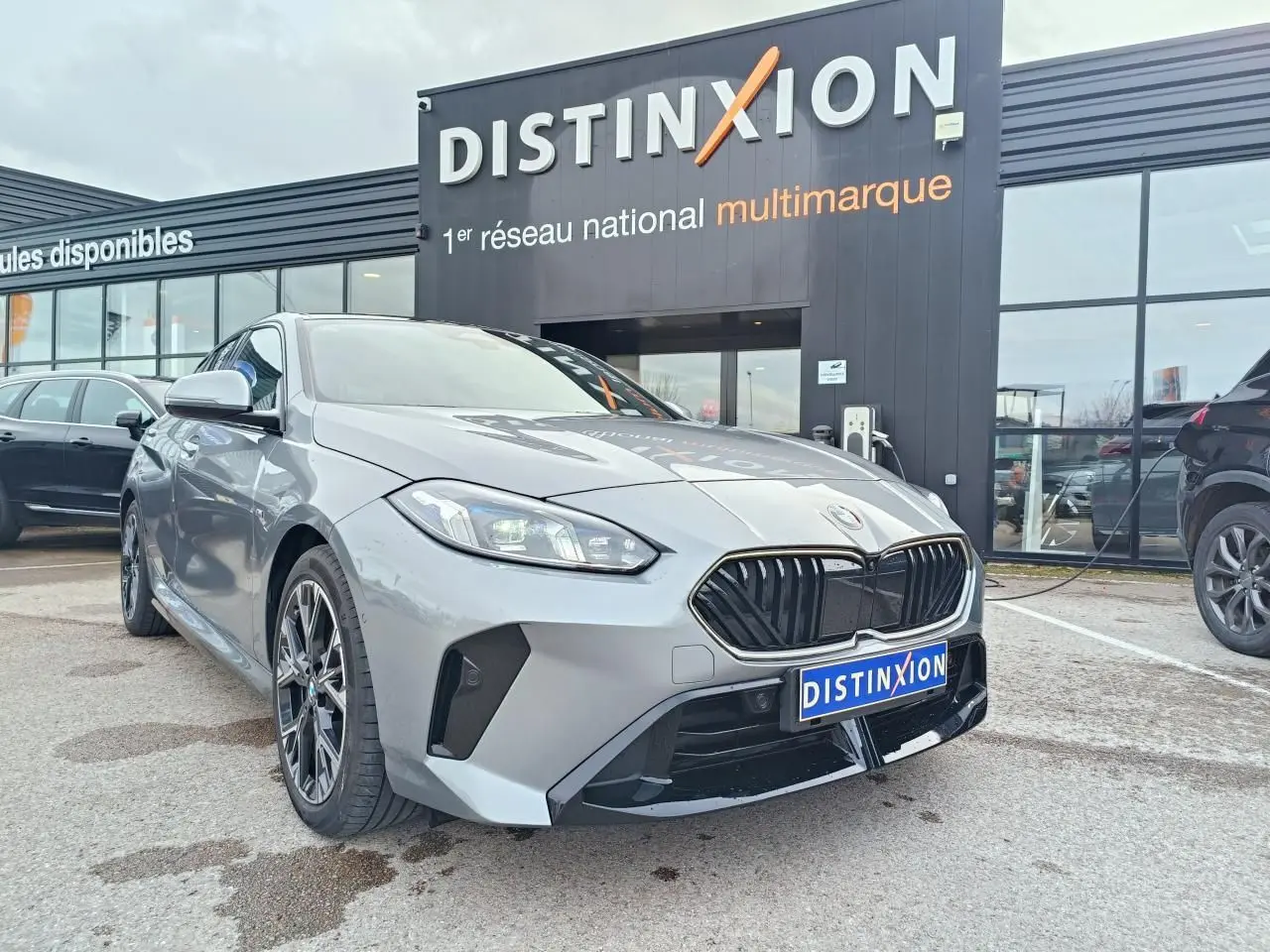 BMW Série 1 gris Skyscraper avec toit noir, vue 3/4 avant mettant en valeur la calandre M Sport et les jantes 18 pouces.