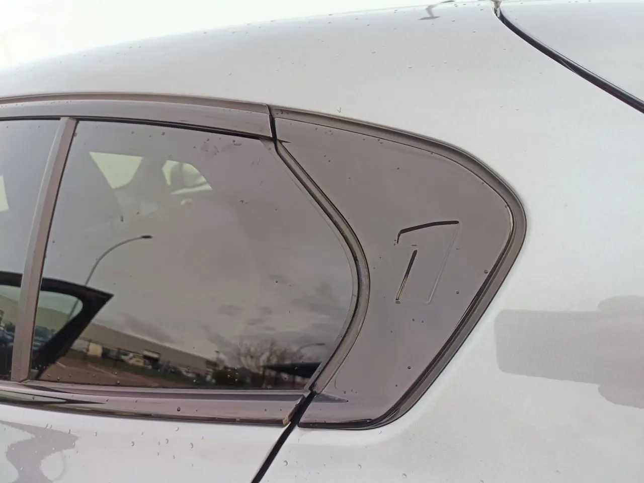 Détail de la vitre arrière droite fumée sur BMW Série 1 gris Skyscraper avec toit noir.