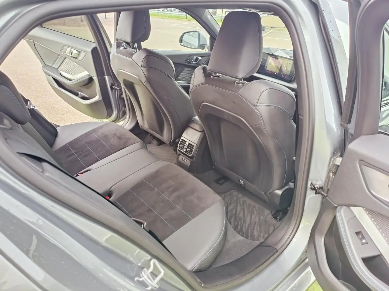 Vue intérieure arrière côté gauche de la BMW Série 1 120 M Sport gris Skyscraper avec sellerie Alcantara noire et surpiqûres bleues.