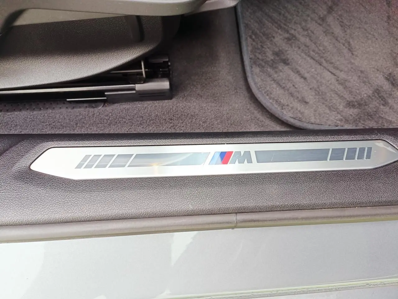 Détail de la plaque M sur le seuil de porte côté conducteur d'une BMW Série 1 gris Skyscraper avec intérieur noir.