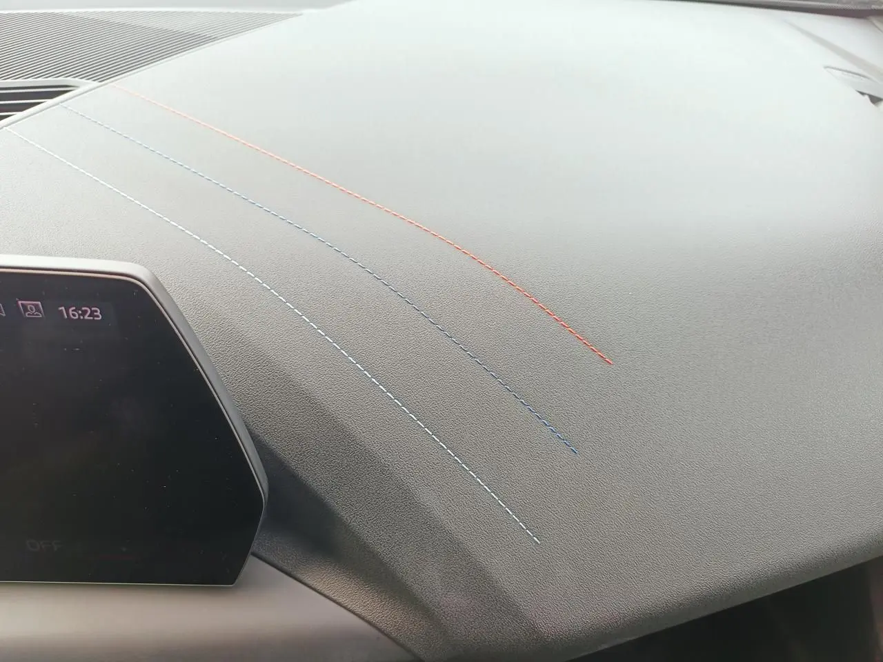 Détail du tableau de bord gris avec surpiqûres tricolores bleu clair, bleu foncé et rouge sur BMW Série 1 F70.