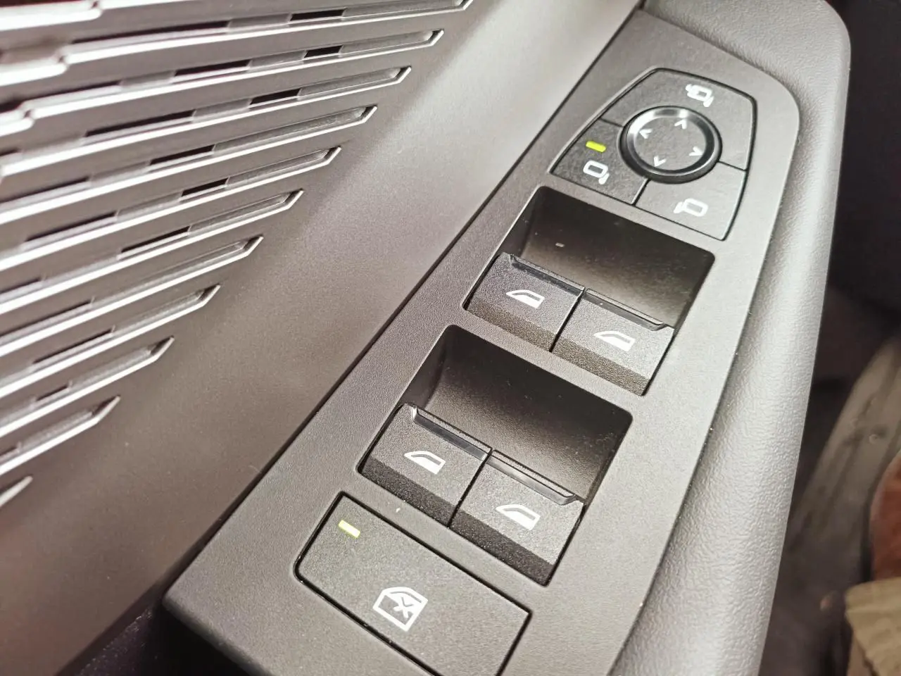 Gros plan sur les commandes des vitres et rétroviseurs côté conducteur de la BMW Série 1 F70 gris Skyscraper avec inserts aluminium.