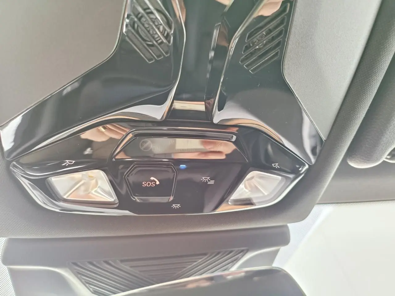 Vue en contre-plongée du plafonnier noir brillant avec bouton SOS et éclairages intégrés dans une BMW Série 1 2025 gris Skyscraper.