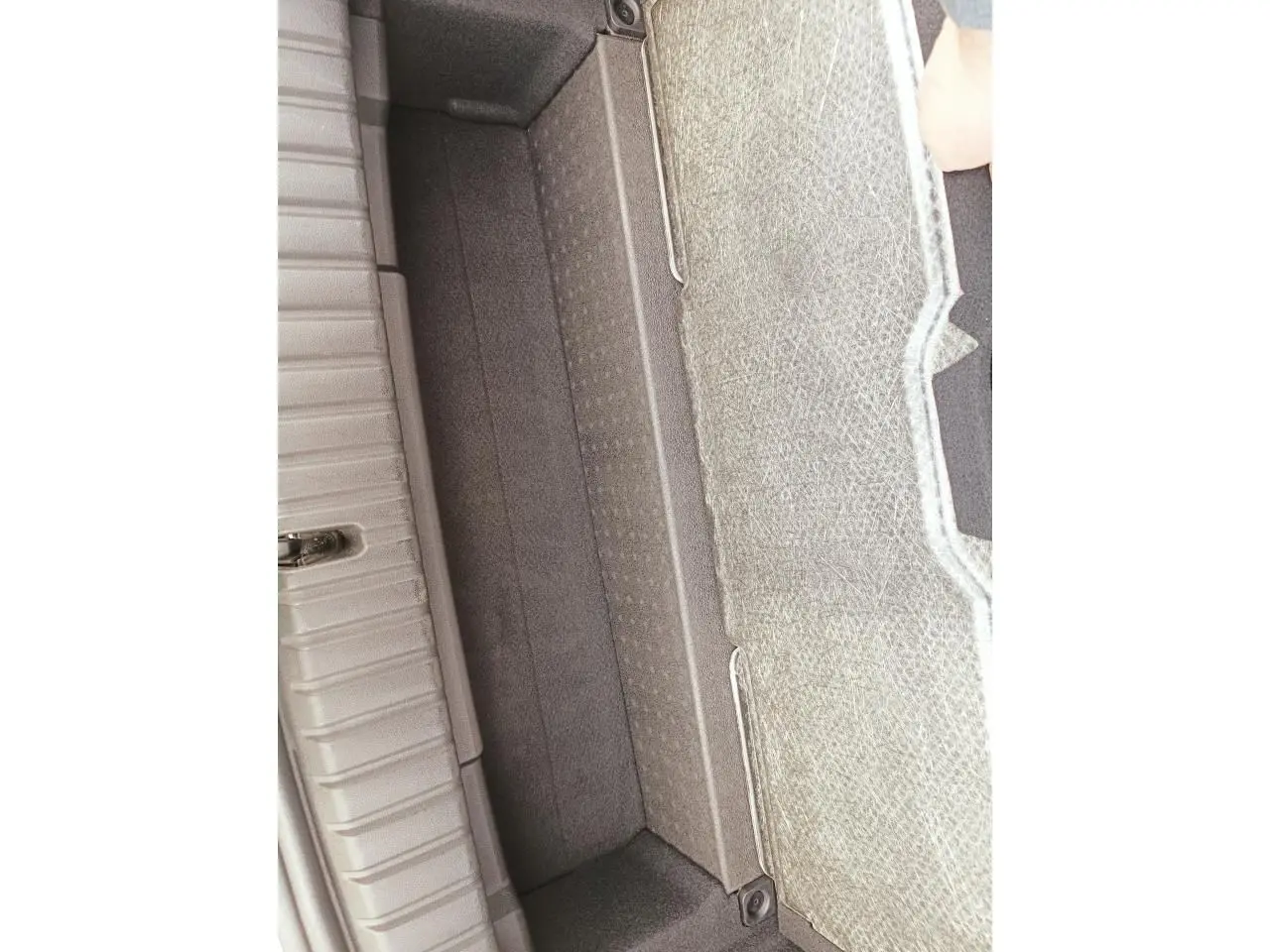 Vue en plongée sur le compartiment de rangement sous le plancher du coffre de la BMW Série 1 F70 120 M Sport gris Skyscraper.