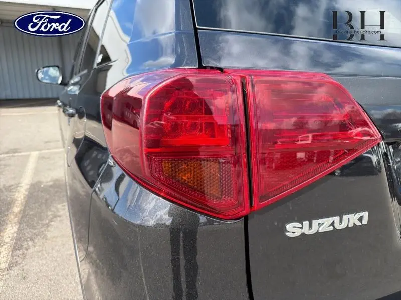 Gros plan sur le feu arrière droit d’un Suzuki Vitara Cosmic Black Pearl métallisé, avec logo Suzuki visible.