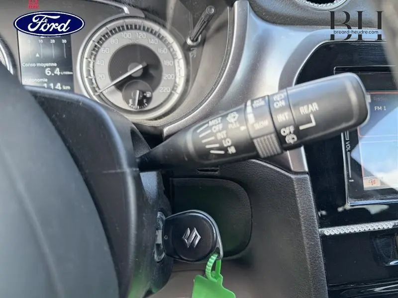 Vue rapprochée du tableau de bord et du commodo d’essuie-glace d’un Suzuki Vitara noir, avec clé insérée.