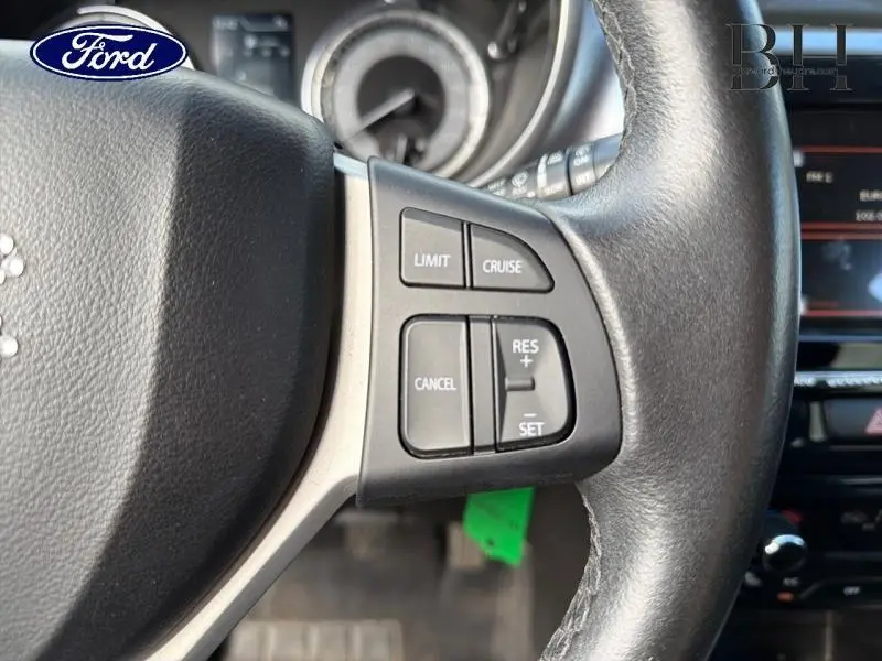 Gros plan sur le côté droit du volant cuir noir d'un Suzuki Vitara 2019, avec commandes de régulateur de vitesse.
