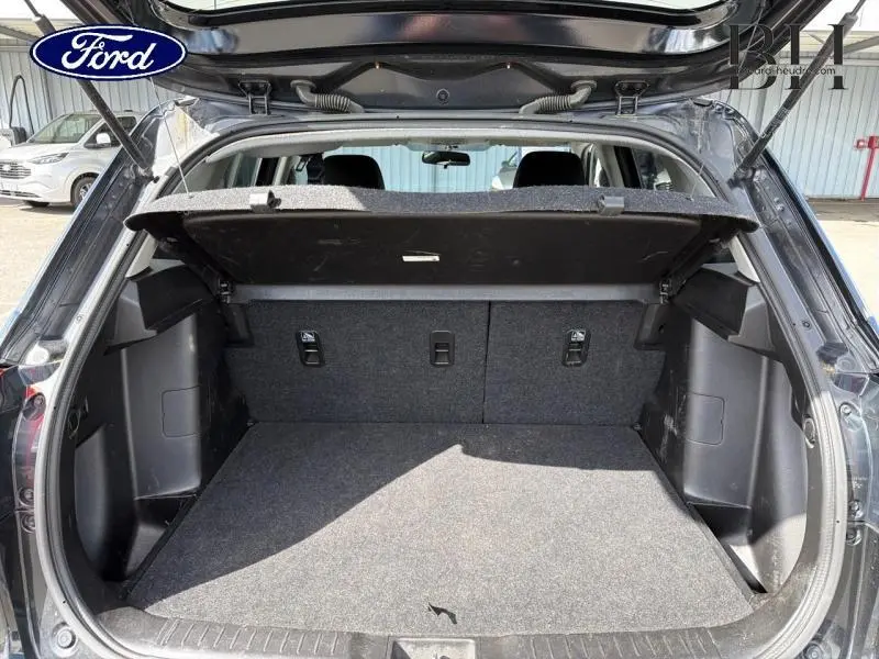 Coffre ouvert vu de l'arrière du Suzuki Vitara Cosmic Black Pearl métallisé, montrant la banquette rabattable et le cache bagages.
