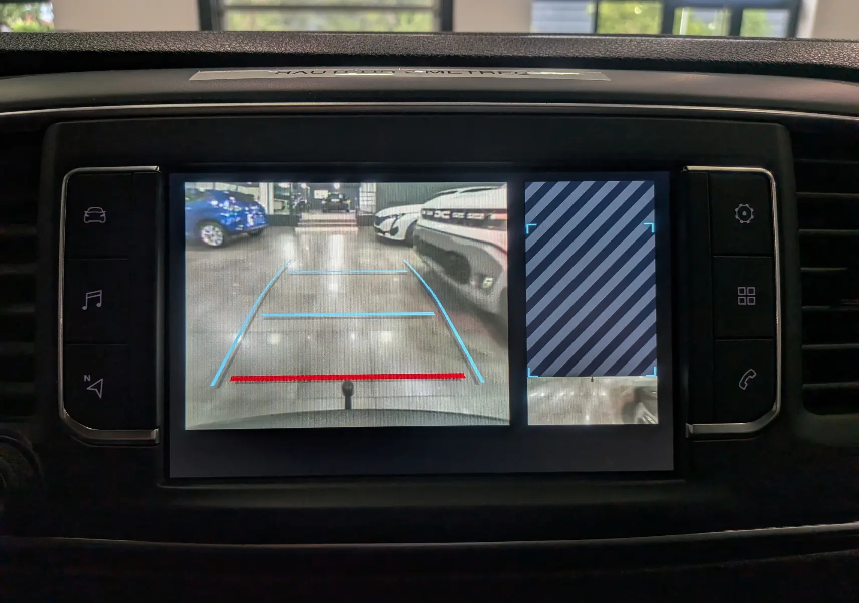 Écran de caméra de recul du Peugeot Expert Fourgon gris acier, avec lignes de guidage et vue sur véhicules en arrière-plan.