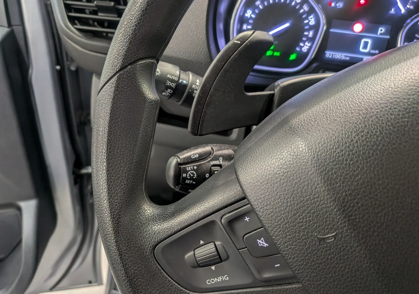 Gros plan sur le volant noir côté gauche du Peugeot Expert Fourgon 2023, avec commandes intégrées et tableau de bord en arrière-plan.