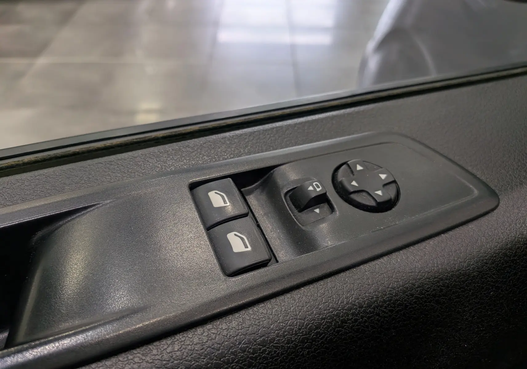 Gros plan sur les commandes de réglage des rétroviseurs et vitres côté conducteur du Peugeot Expert Fourgon gris acier.