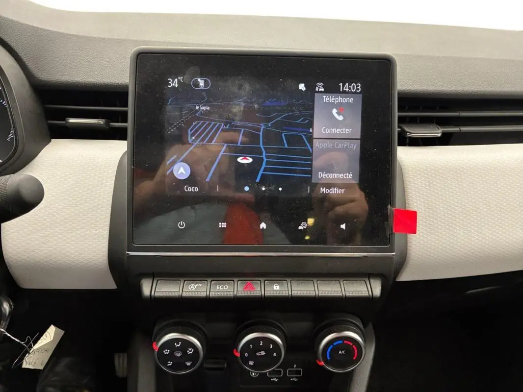 Vue rapprochée du tableau de bord de la Renault Clio noire 2023, avec écran tactile et commandes manuelles de climatisation.