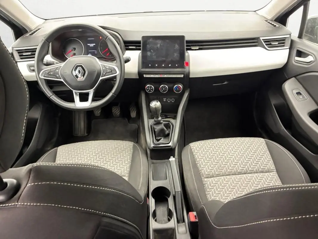 Vue intérieure avant de la Renault Clio V TCe 100 GPL Evolution 2023, tableau de bord noir et sièges tissu gris à motifs.