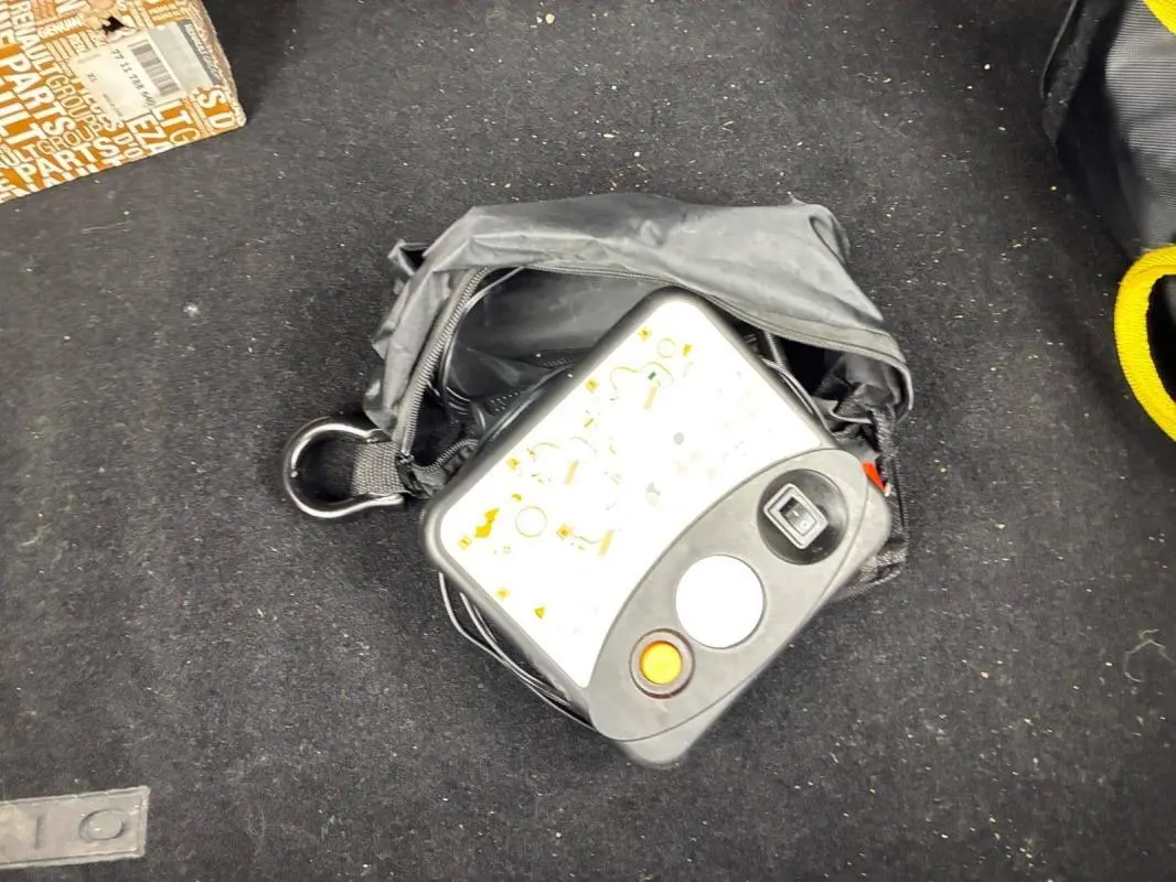 Sac noir avec compresseur de pneu posé sur le tapis de coffre d’une Renault Clio V TCe 100 GPL noir 2023.