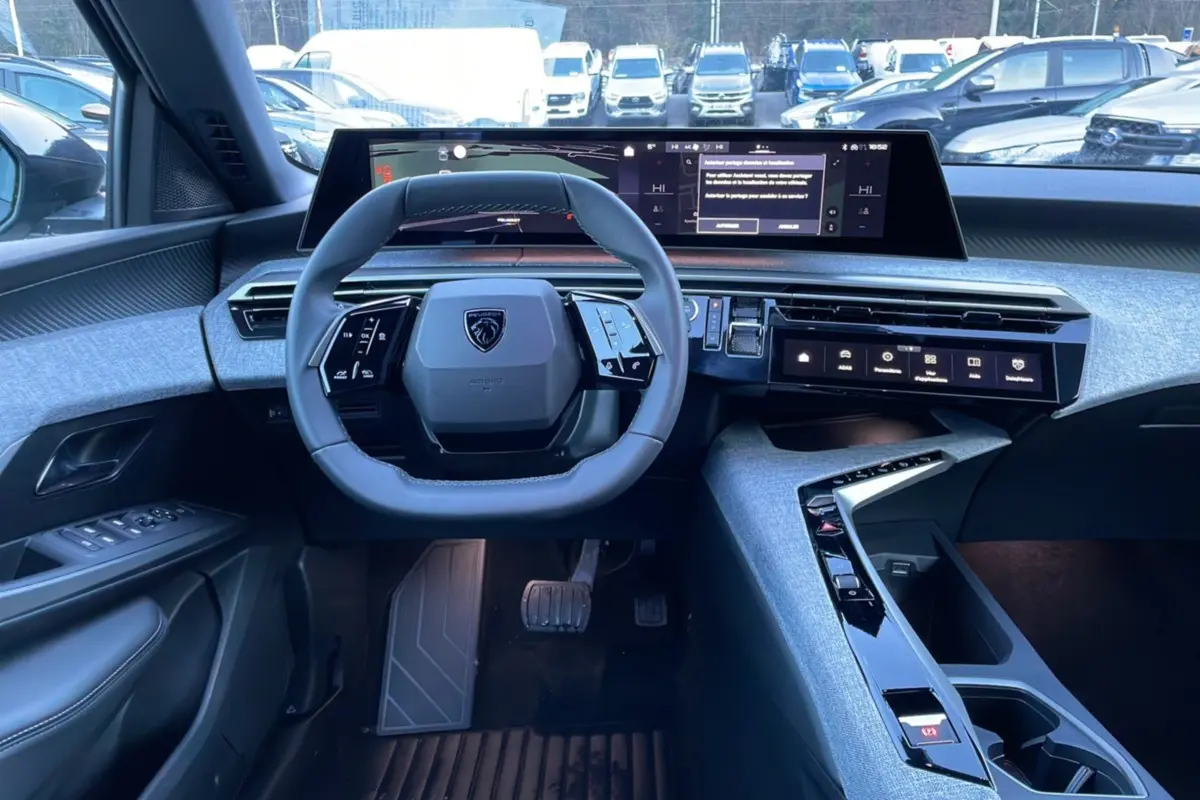 Vue intérieure du poste de conduite du Peugeot 5008 Hybrid 145 Allure Plus 2025, avec volant compact et écran digital large.