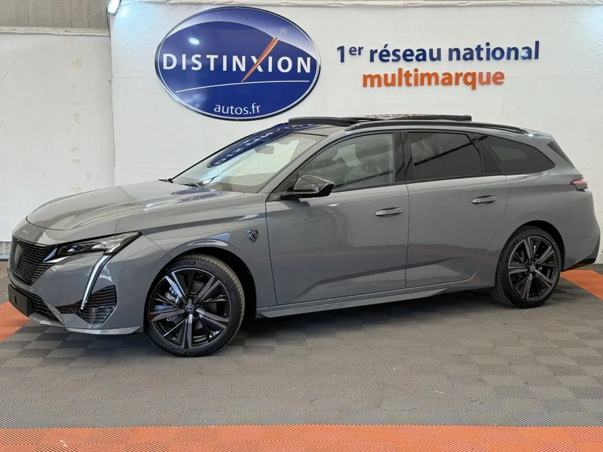 Profil côté gauche d'une Peugeot 308 Hybrid 136 e-DCS6 GT gris foncé avec jantes noires et vitres teintées en showroom.