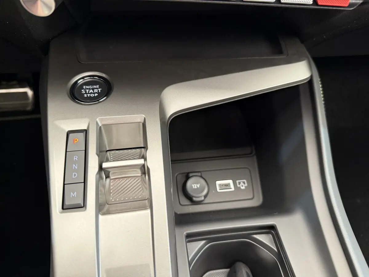 Vue rapprochée de la console centrale gris clair de la Peugeot 308 Hybrid 136 e-DCS6 GT avec bouton start et levier de vitesses automatique.