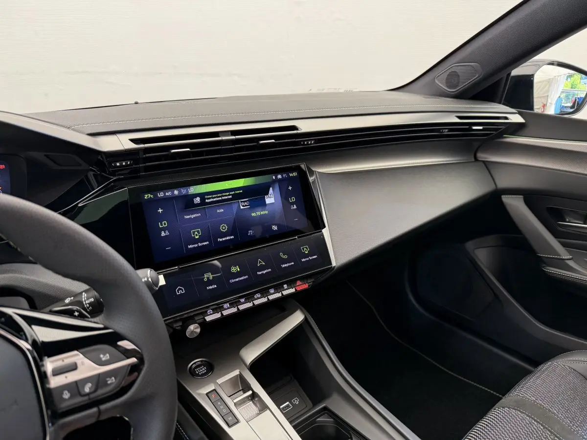 Intérieur avant droit de la Peugeot 308 Hybrid 136 e-DCS6 GT 2024, tableau de bord moderne gris foncé avec écran tactile central.