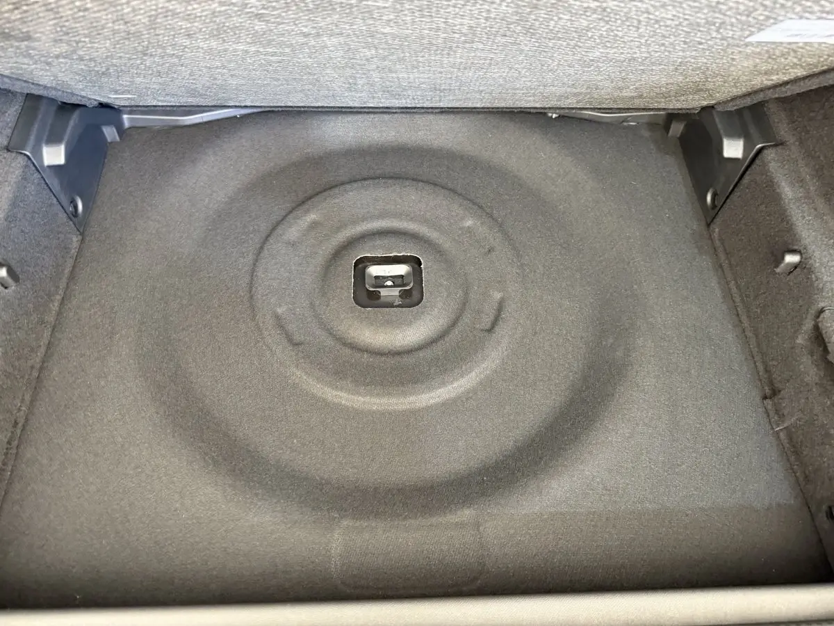 Coffre ouvert de la Peugeot 308 Hybrid 136 e-DCS6 GT 2024, vue intérieure sur le rangement sous plancher gris foncé.