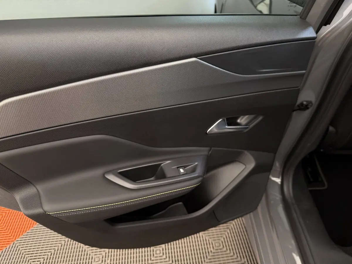 Gros plan sur la porte arrière droite grise du Peugeot 308 Hybrid 136 e-DCS6 GT avec surpiqûres vertes visibles.