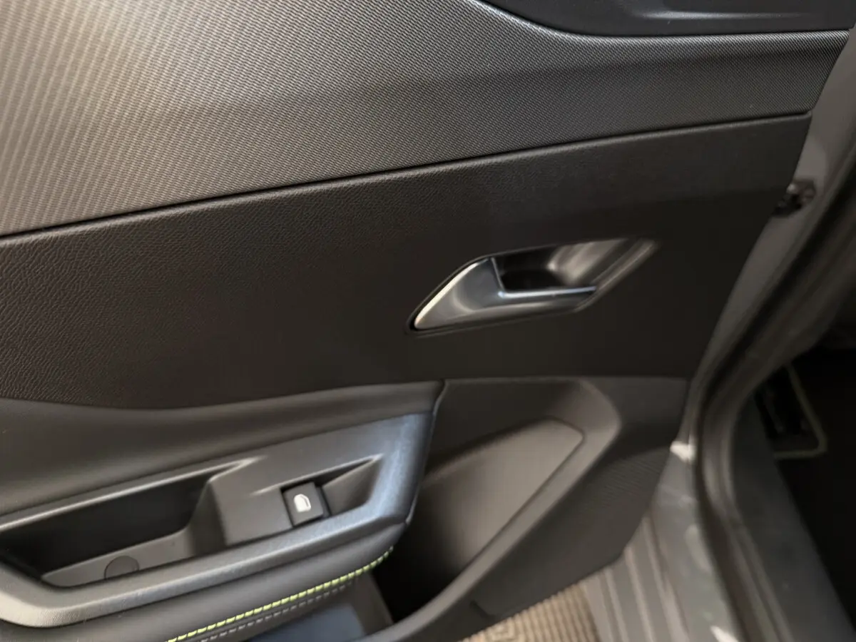 Gros plan sur la porte côté conducteur gris foncé de la Peugeot 308 Hybrid 136 e-DCS6 GT avec poignée et bouton de verrouillage.