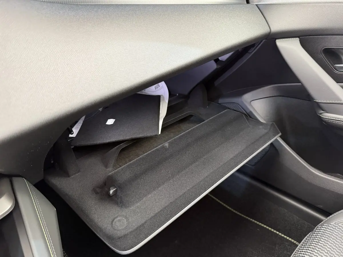 Gant de boîte à gants ouvert côté passager dans l'habitacle gris foncé d'une Peugeot 308 Hybrid 2024.