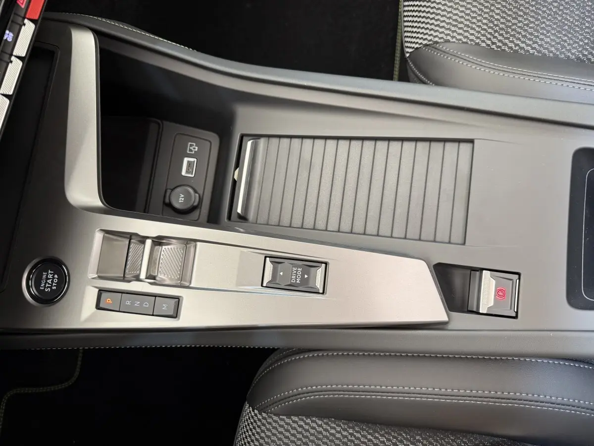 Console centrale gris clair de la Peugeot 308 Hybrid 136 e-DCS6 GT 2024 avec commandes boîte auto et bouton start/stop.