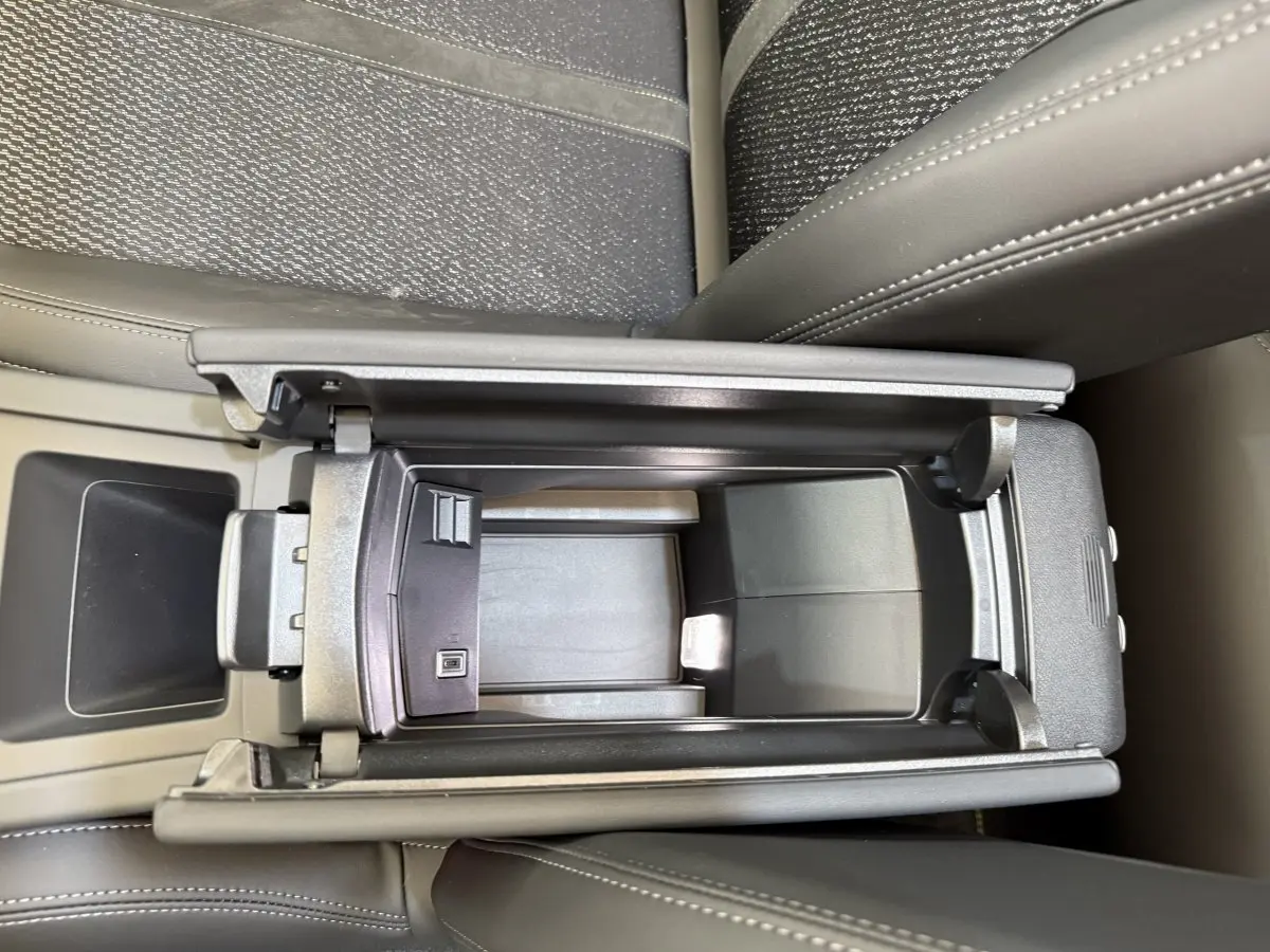 Vue plongeante sur le rangement central ouvert de la Peugeot 308 Hybrid 136 e-DCS6 GT avec sellerie gris foncé et coutures visibles.