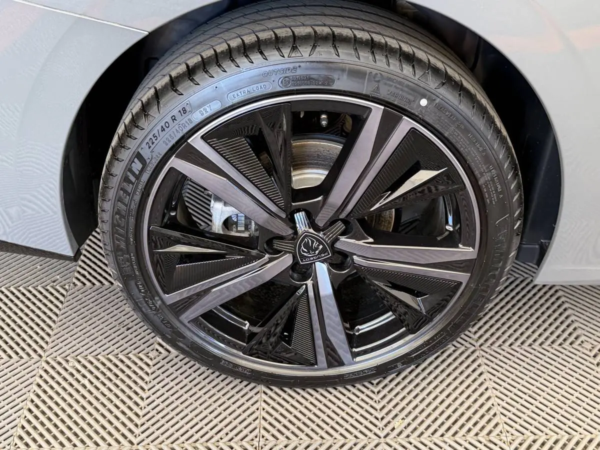 Gros plan sur la jante noire et argentée du côté gauche d'une Peugeot 308 Hybrid 136 e-DCS6 GT gris foncé.