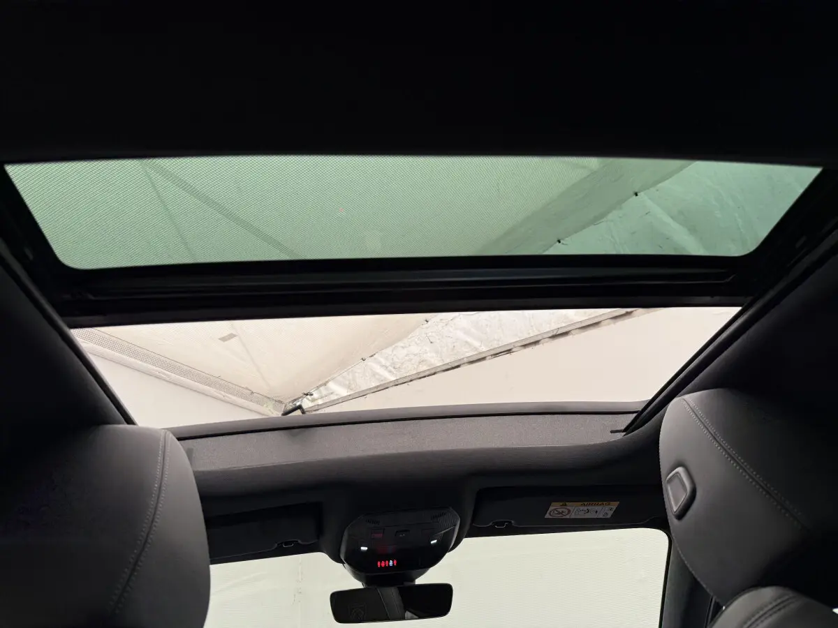 Vue intérieure du toit ouvrant panoramique de la Peugeot 308 Hybrid 136 e-DCS6 GT gris foncé, avec ciel visible à travers le verre.