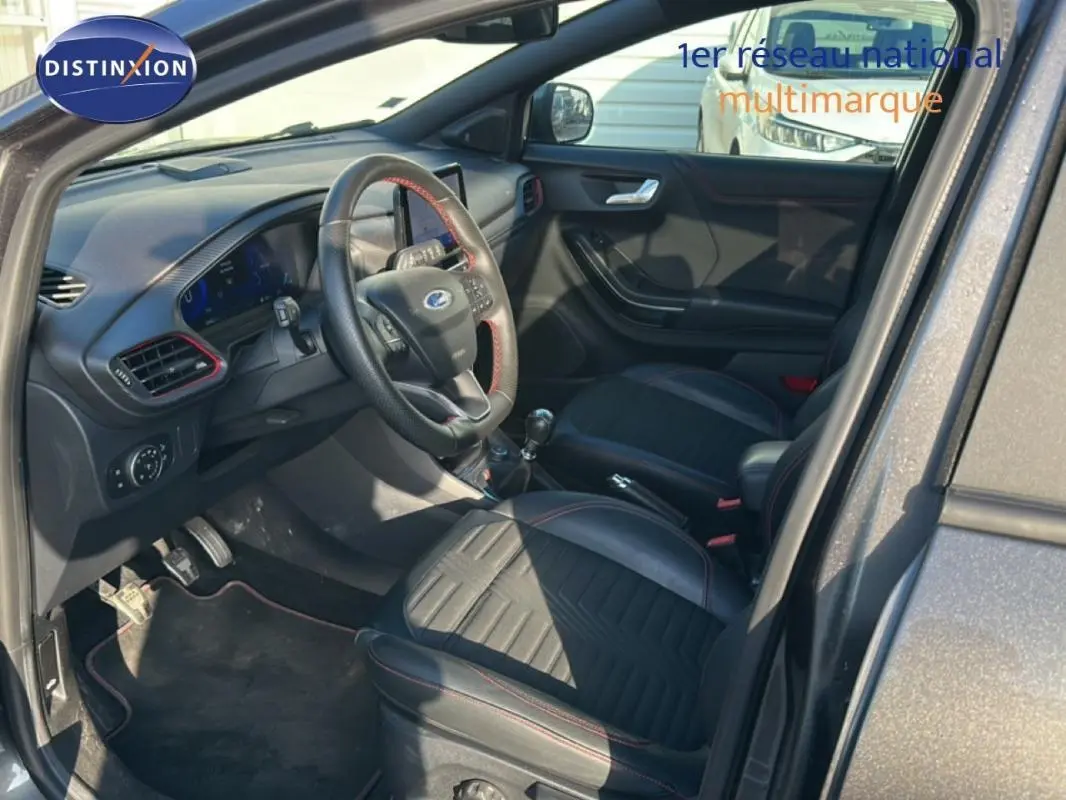 Vue intérieure côté conducteur du Ford Puma gris foncé 2020, avec sièges noirs et volant sport à surpiqûres rouges.