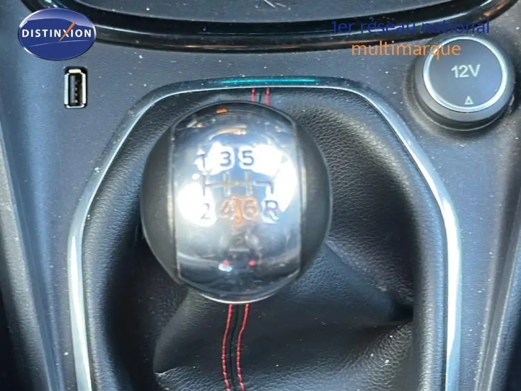 Gros plan sur le levier de vitesses manuel chromé de la Ford Puma gris foncé, avec coutures rouges visibles.