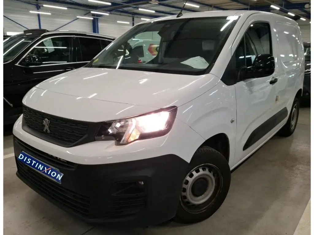 Vue 3/4 avant droit du Peugeot Partner Fourgon blanc 2022 avec phares allumés et pare-chocs noir mat distinctif.