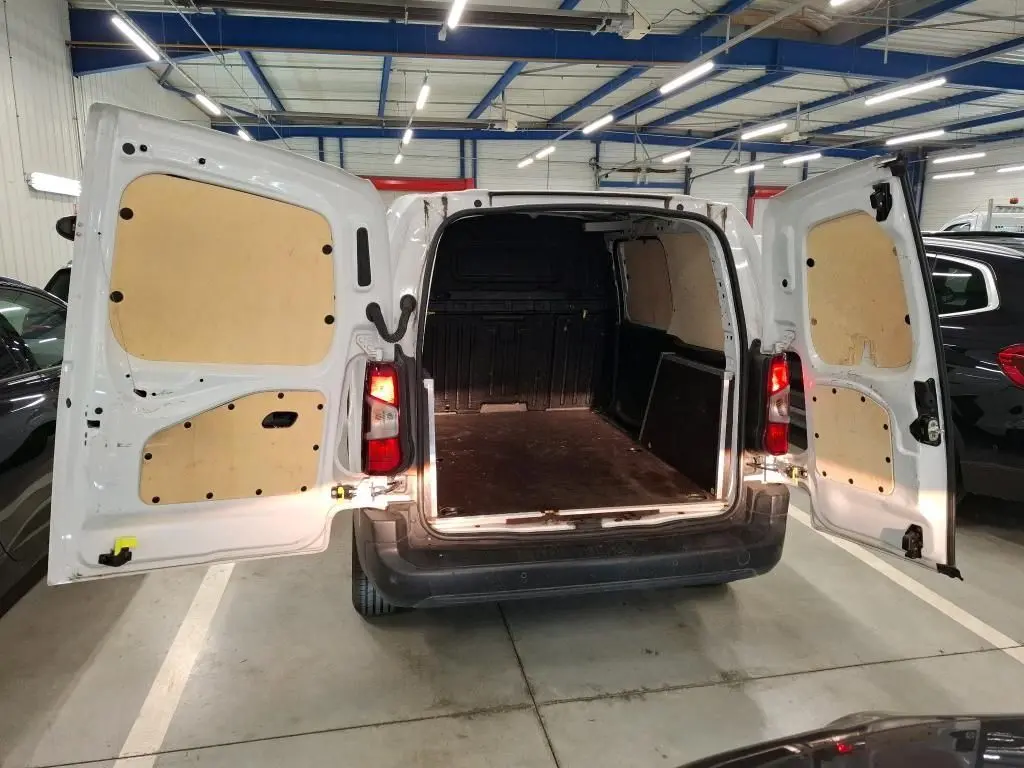 Vue arrière du Peugeot Partner Fourgon blanc 2022 avec portes ouvertes, plancher bois antidérapant et habillage intérieur clair.