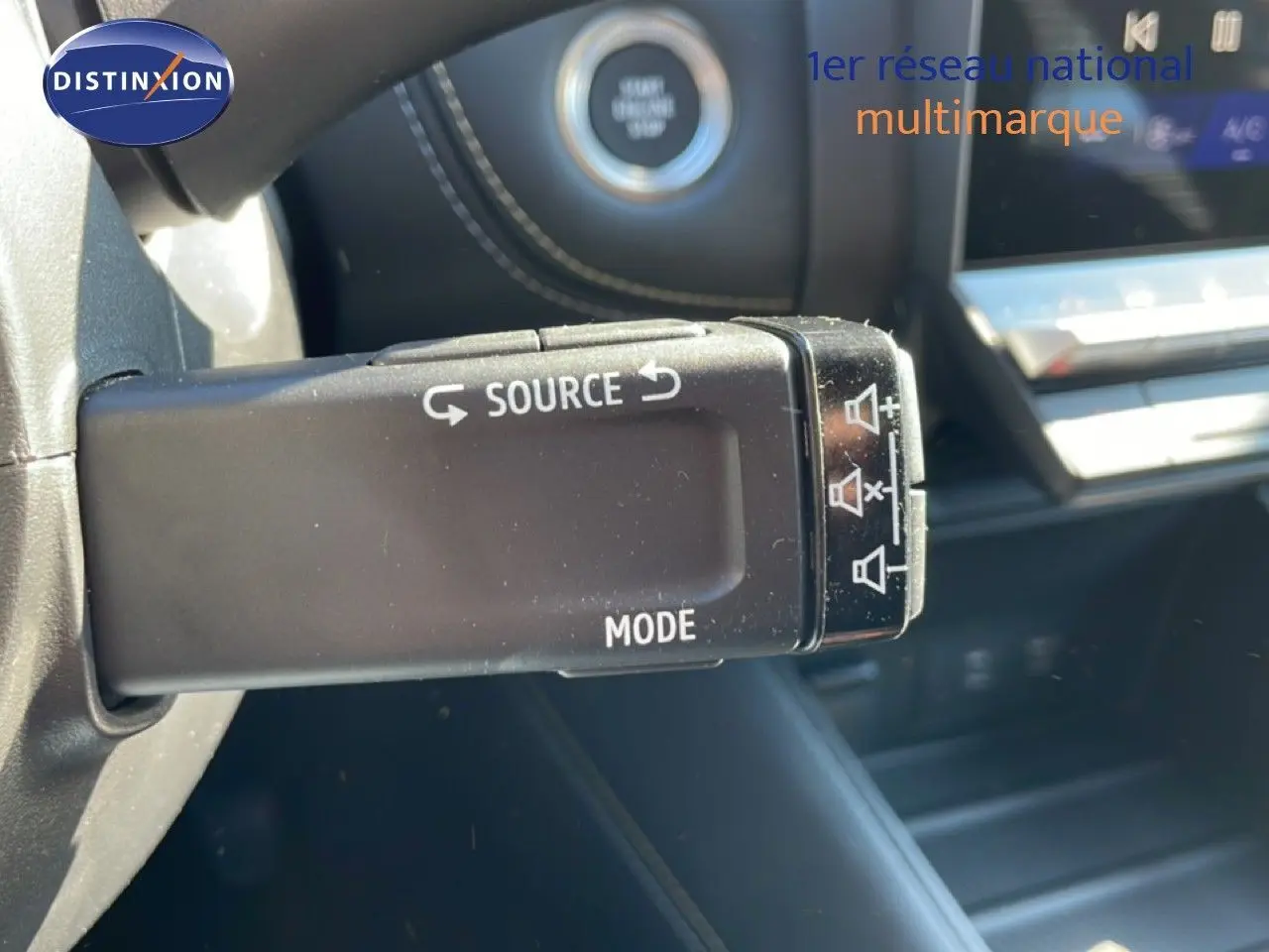 Gros plan sur la commande au volant noir du Renault Symbioz 2025, avec tableau de bord et bouton start visible en arrière-plan.