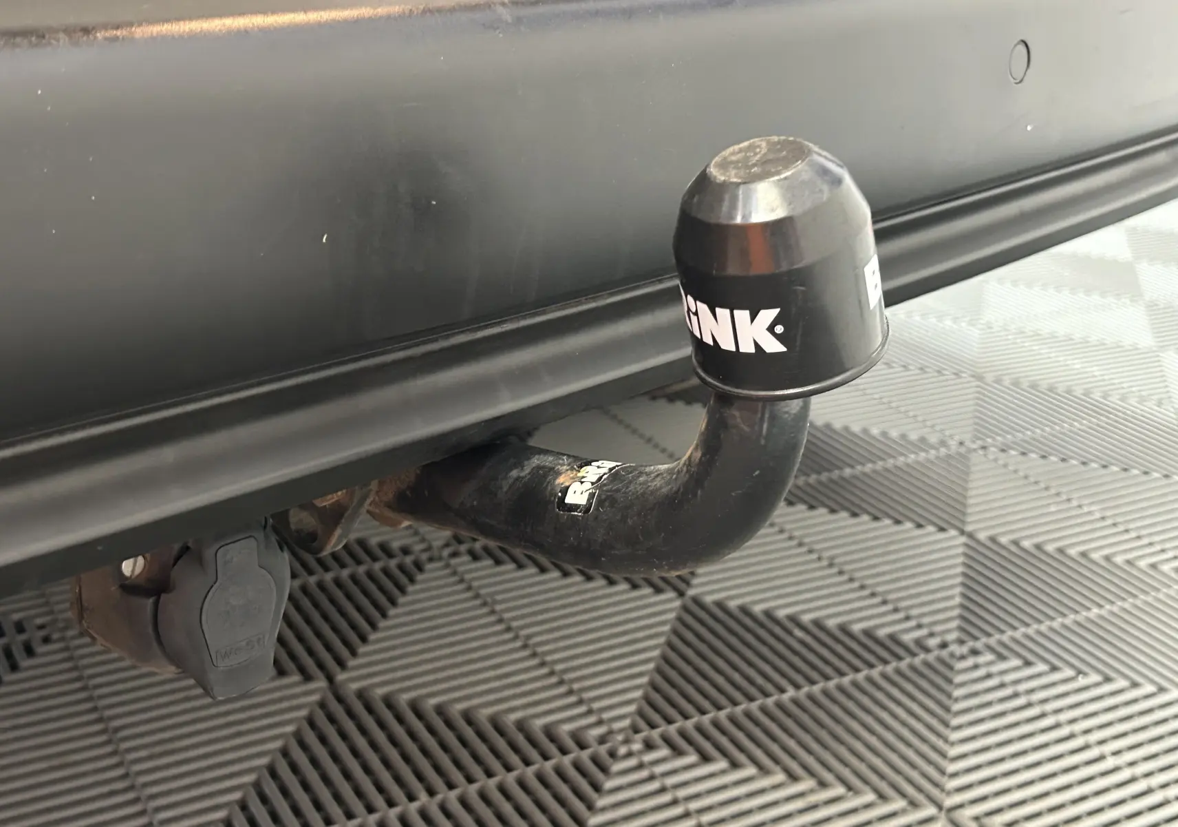 Gros plan sur l'attelage noir fixé à l'arrière d'un Peugeot Rifter gris sable de 2019.