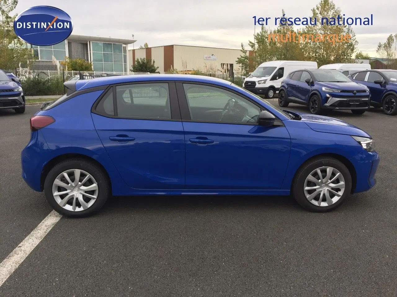 Profil côté gauche d'une Opel Corsa 2025 bleu voltaik metal garée sur un parking, avec jantes argentées et vitres teintées.