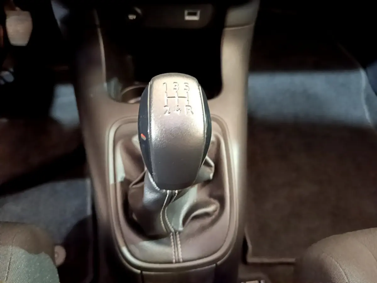 Le levier de vitesses manuel noir de la Citroën C3 blanche, vu de dessus dans l'habitacle.