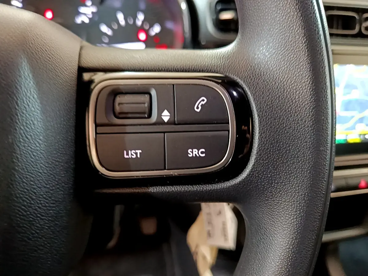 Gros plan sur les commandes gauche du volant noir de la Citroën C3 PureTech 2019 avec écran tactile en arrière-plan.