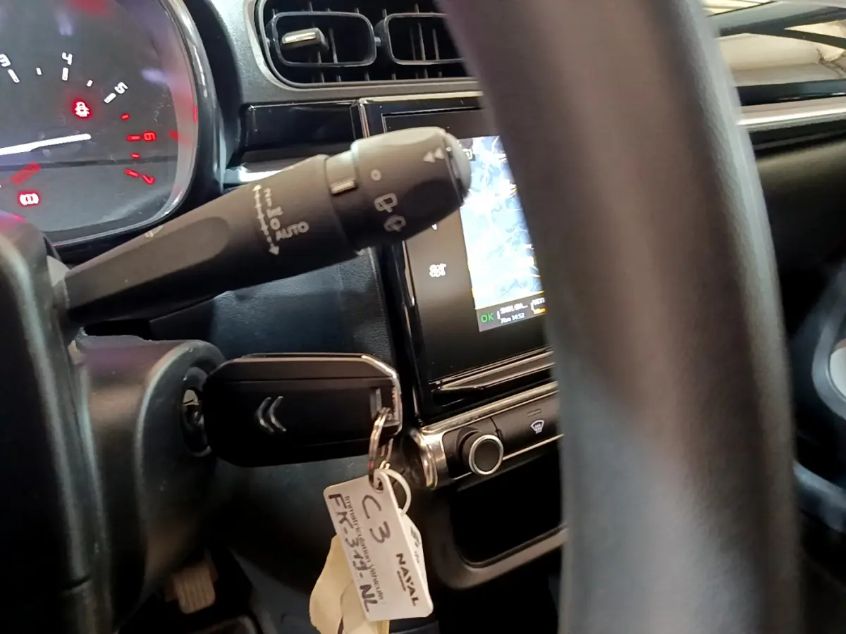 Vue rapprochée de l'intérieur de la Citroën C3 blanche 2019, montrant le volant, clé et écran tactile de navigation.
