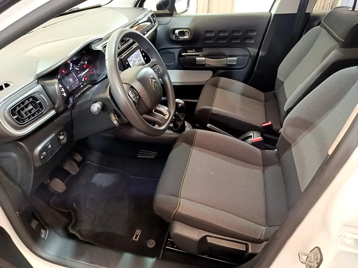 Intérieur avant droit de la Citroën C3 blanche 2019, montrant sièges gris, volant multifonctions et tableau de bord tactile.