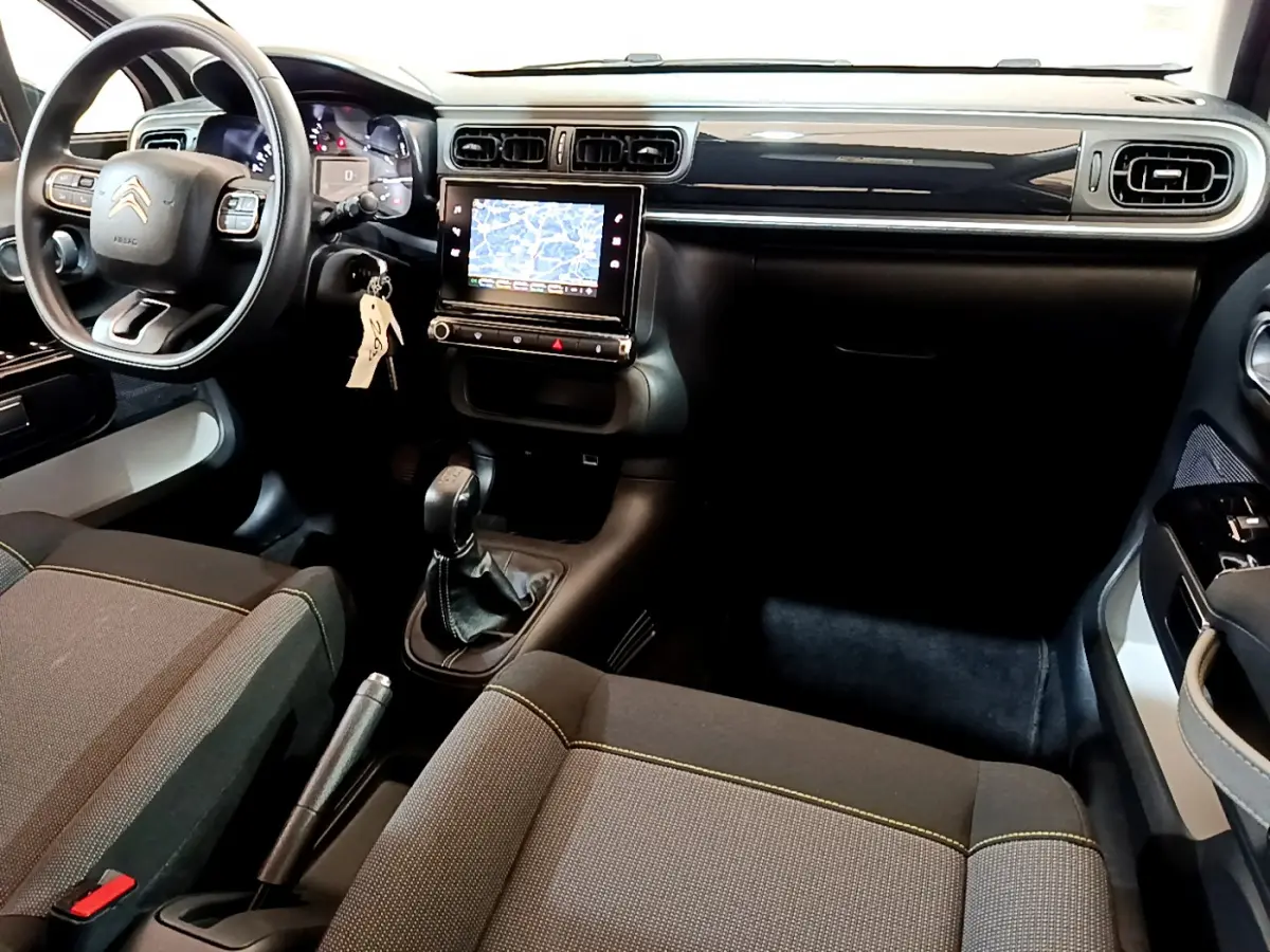 Intérieur avant droit d'une Citroën C3 blanche 2019 avec tableau de bord noir, écran tactile et boîte manuelle.