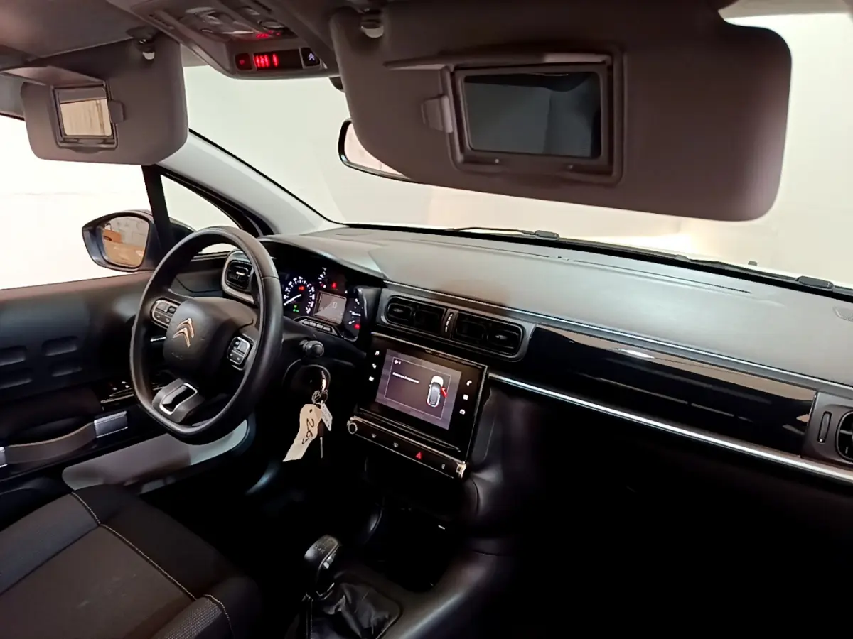 Vue intérieure côté conducteur de la Citroën C3 blanche 2019 avec tableau de bord noir et écran tactile central.