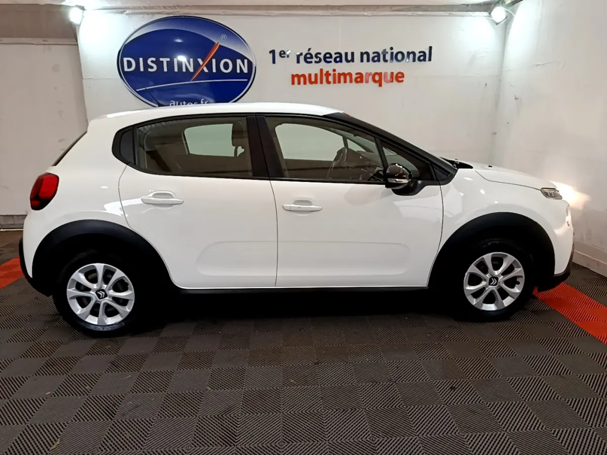 Profil côté droit d'une Citroën C3 blanche 2019 avec protections noires et jantes alliage en showroom.