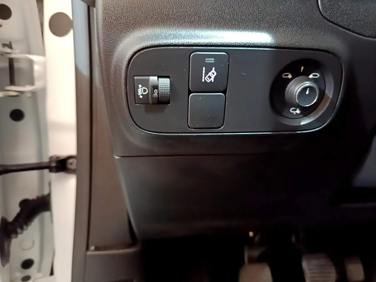 Gros plan sur les commandes d'éclairage et réglage des rétroviseurs côté conducteur d'une Citroën C3 blanche de 2019.