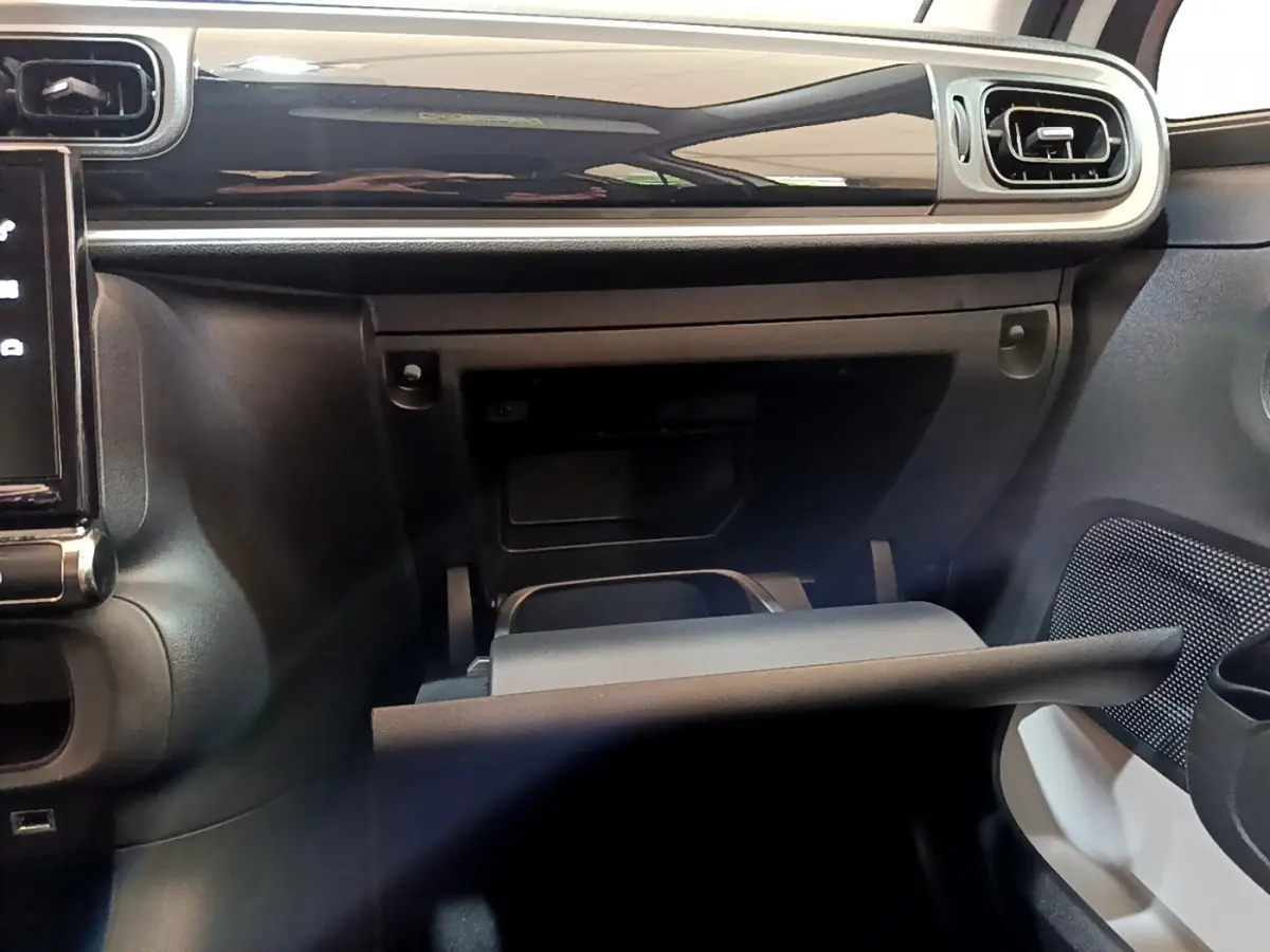 Intérieur de la Citroën C3 blanc, vue du tableau de bord côté passager avec boîte à gants ouverte et finition noire brillante.