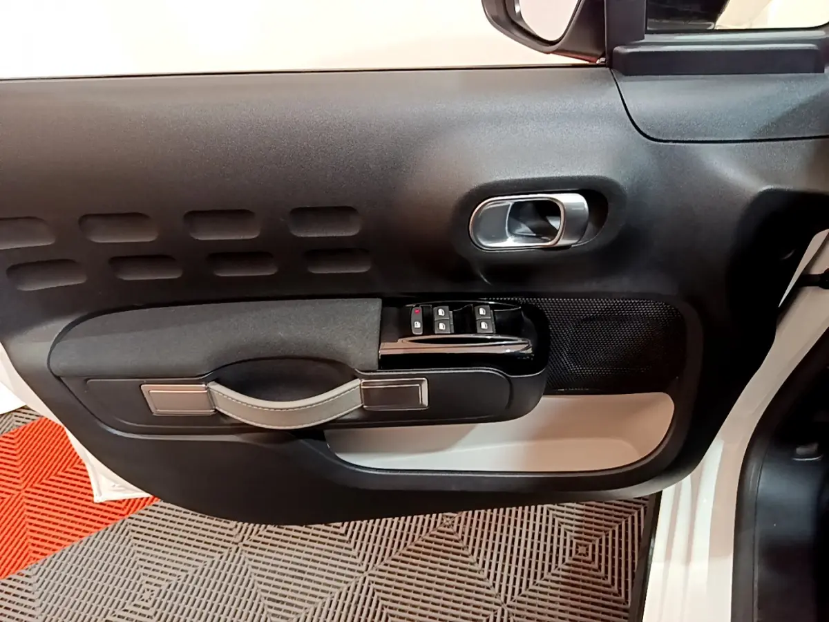 Vue rapprochée de la porte avant gauche blanche d'une Citroën C3 2019, avec commandes de vitres et poignée intégrée.