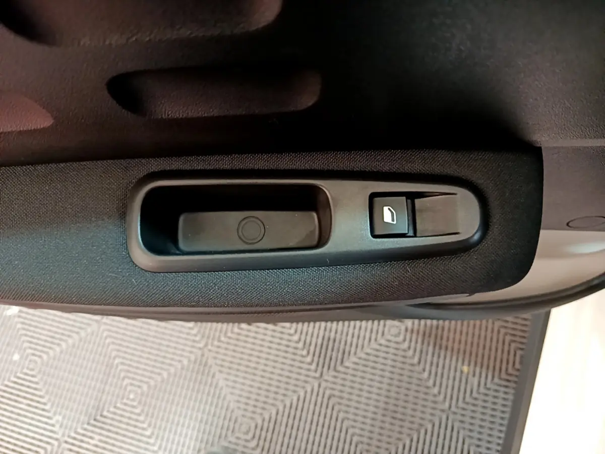 Poignée intérieure noire avec bouton de commande de vitre sur la porte côté gauche d'une Citroën C3 blanche.
