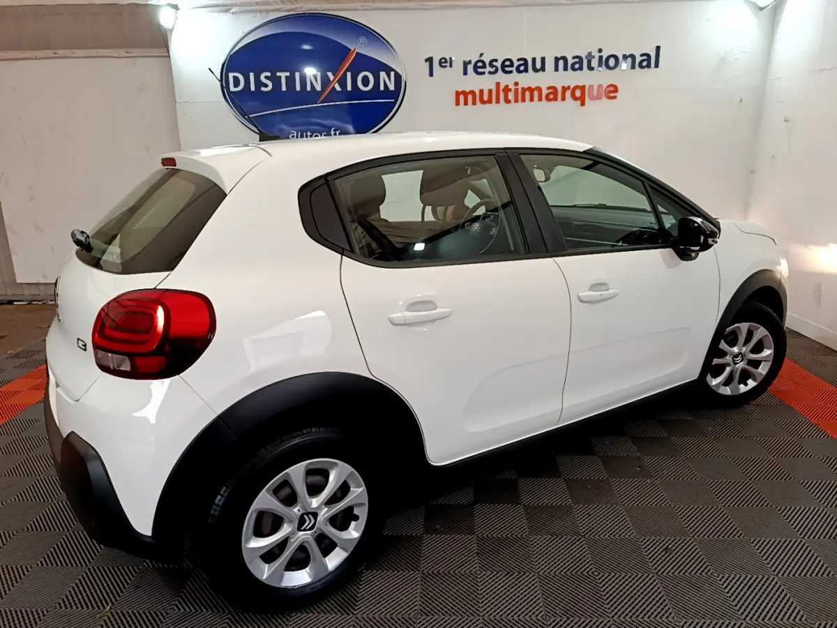 Citroën C3 blanc vue de côté droit arrière, avec jantes alliage et protections noires sur les passages de roues.